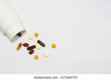 Close-up Photo Of Vitamins And Supplements On White Background With A White Bottle. Including Multi Vitamins, Vitamin B, Vitamin C, Vitamin D, Collagen Tablets, Probiotics Capsules And Iron Capsules.