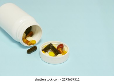 Close-up Photo Of Vitamins And Supplements On Blue Background With A White Bottle. Including Multi Vitamins, Vitamin B, Vitamin C, Vitamin D, Collagen Tablets, Probiotics Capsules And Iron Capsules.