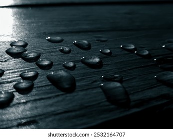 A close-up photo of water droplets glistening on a weathered wooden surface, with the sunlight reflecting off their surface. The droplets create a beautiful pattern of light and dark. - Powered by Shutterstock