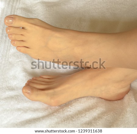 Closeup photo of woman cross bare feet on a white towel