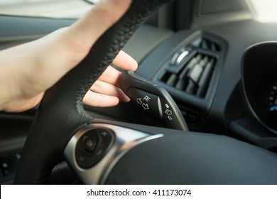 Closeup photo of woman driving car and using turn signal switch