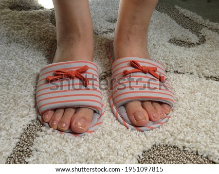 Closeup photo of woman feet in slippers standing on carpet