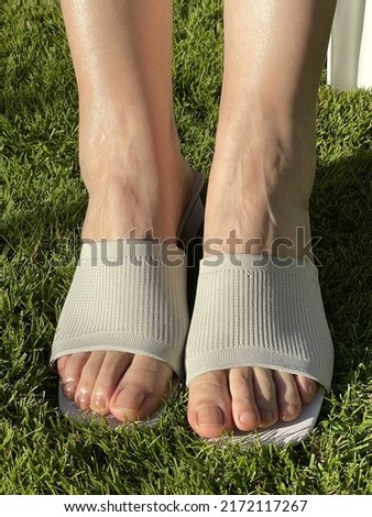 Closeup photo of woman feet in summer fashion sandals with grass background