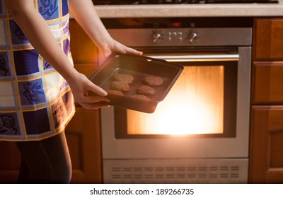 Closeup Photo Of Woman Putting Cookies In Oven