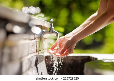 Closeup photo of woman washing hands in a city fountain 