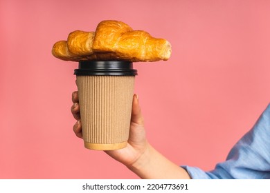 Close-up photo of woman's hand holding croissant. Isolated portrait of woman with fast food and cup of coffee over pink background. Diet breakfast concept. - Powered by Shutterstock