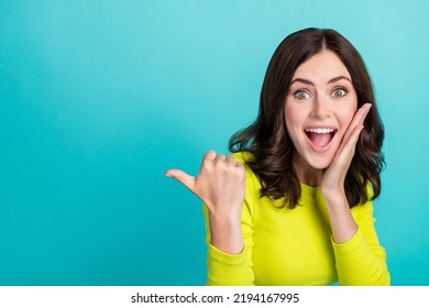 Closeup Photo Of Young Attractive Girlish Woman Shocked Touch Cheeks Funny Directing Finger Empty Space Unexpected Isolated On Cyan Color Background