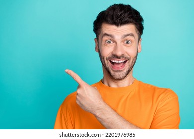 Closeup Photo Of Young Attractive Handsome Funny Reaction Man Wear Orange T-shirt Positive Impressed Finger Pointing Empty Space Offer Isolated On Cyan Color Background