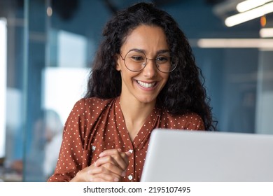 Close-up photo of young beautiful business woman with curly hair and glasses Hispanic woman talking on video call using laptop for remote communication and conference