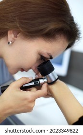 Close-up photo of young brunette woman dermatologist examines nevus or birthmarks on patients hand with dermatoscope. Prevention of melanoma, mole control. Professional dermoscopy concept