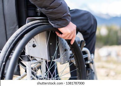 Closeup Photo Of Young Disabled Man Holding Wheelchair Outside In Nature Observing Mountains And Nature