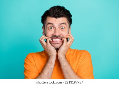 Closeup photo of young handsome attractive bearded man wear stylish orange t-shirt gnaw bite nails nervous isolated on aquamarine color background
