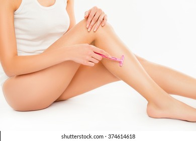 Closeup photo of young slim woman shaving her leg
