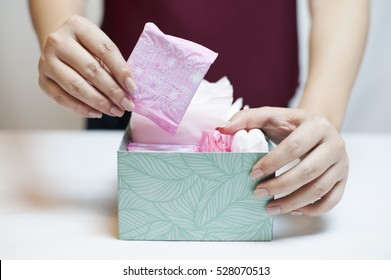 Closeup Photo Of Young Woman Picking Sanitary Pad Out Of Green Box