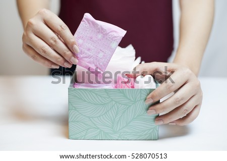 Closeup photo of young woman picking sanitary pad out of green box