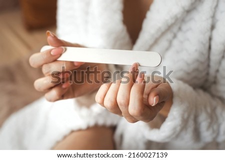 Closeup photo of young womans hand makes herself a manicure, files her nails with a nail file. Personal hygiene