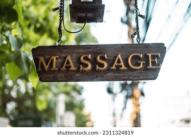 A close-up photograph of a sign for a massage parlor displayed prominently on the side of a building
