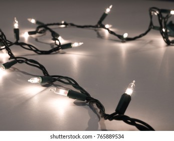 Close-up Photograph Of A Strand Of Real White Christmas String Lights With A Dark Background Making A Festive Holiday Backdrop.