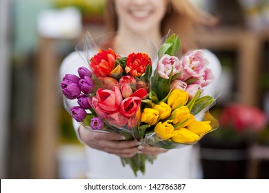 Closeup photograph of a woman showing a bunch of assorted flowers.