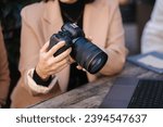 Close-up of photographer holding mirrorless camera and checking pictures. 
