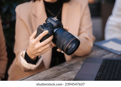 Close-up of photographer holding mirrorless camera and checking pictures. 