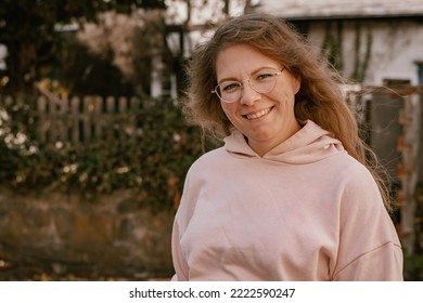 Close-up photography of a 30 years old woman showing a cute smile and looking straight into the camera; the woman is wearing a pink hoodie; the picture was taken outdoors in countryside - Shutterstock ID 2222590247