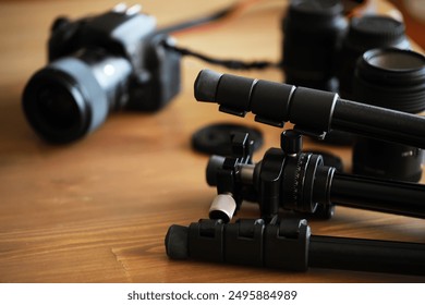 Close-Up of Photography Equipment: DSLR Camera, Lenses, and Tripod on Wooden Surface - Powered by Shutterstock