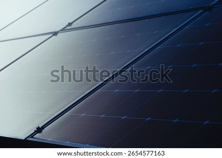Close-up of a photovoltaic array, multiple solar panels connected in rows. The panels are dark and reflective, capturing sunlight to generate sustainable and renewable power for various applications.