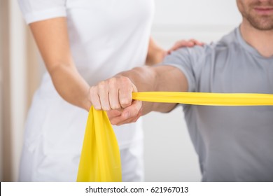 Close-up Of A Physiotherapist Giving Man A Training With Exercise Band