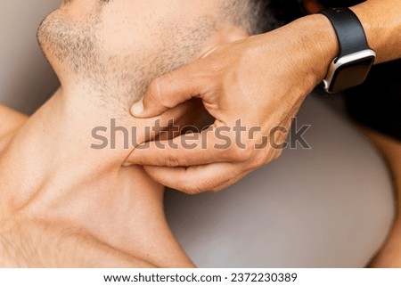 A close-up of a physiotherapist's hand performing a pressure inhibition on the sternocleidomastoid muscle to a patient to relieve pain. Concept of myofascial techniques, elimination of trigger points.