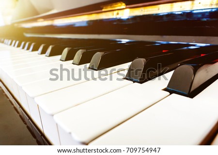 closeup of piano keys. black and white piano keyboard background. close piano key side view. orange light flare reflect piano key background. 