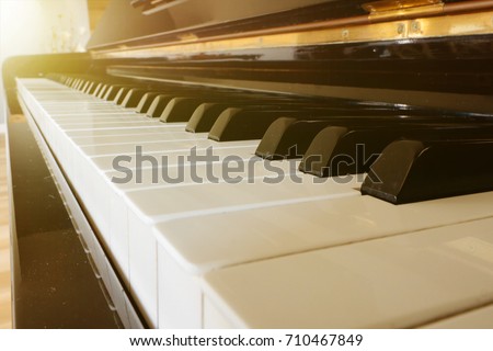 closeup of piano keys. black and white piano keyboard background. close piano key side view. orange light flare reflect piano key background. 