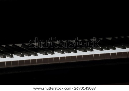 Close-up of piano keys with dramatic lighting and shadow contrast.