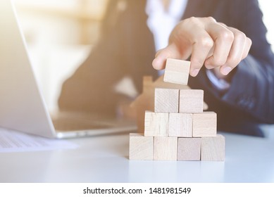 Closeup picture of a businessman placing wooden blocks to represent the peak of the boom to grow their business goals, financial statistics.
 - Powered by Shutterstock