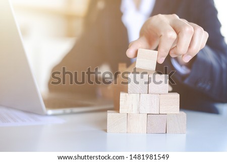Closeup picture of a businessman placing wooden blocks to represent the peak of the boom to grow their business goals, financial statistics.
