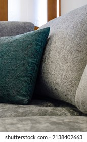 Close-up picture of grey soft with side pillows are comfortable, yet stylish and modern, for the whole family to spend their free time resting under the light passing through the window. Vertical phot