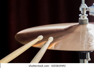 Close-up picture of a hi-hat cymbal and a drumsticks at the studio