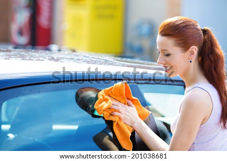 Closeup picture, image young woman, driver, dry wiping  her car with microfiber cloth after washing it, cleaning auto, automobile windows. Transportation self service, care concept. Paint protection