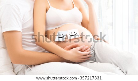 Close-up picture of man and woman awaiting a baby. Male hands on a pregnant belly. 