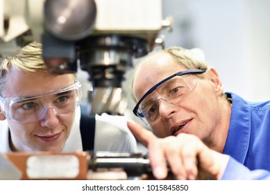 Closeup Picture: Trainer And Apprentice In Vocational Training On A Milling Machine - Teacher Explains Details Of The Machine 