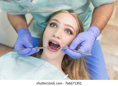 Close-up picture of young woman sitting in the dentist's chair with opened mouth at dentist's office while having examination.