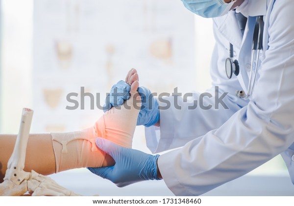Close-up of pictures of a male orthopedic doctor\
or orthopedic doctor Wear a medical mask and medical gloves. Going\
to analyze the cause of ankle bone degeneration In his office at\
the hospital