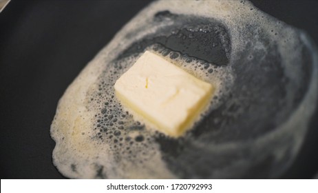 Close-up Of Piece Of Butter Melting In Frying Pan. Action. Cooking Dish In Frying Pan With Melted Piece Of Butter. Fat Butter Melts In Hot Pan