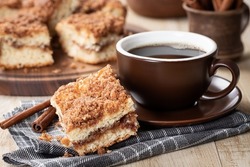 Closeup Of A Piece Of Cinnamon Crumb Cake And Cup Of Coffee On A Wooden Table