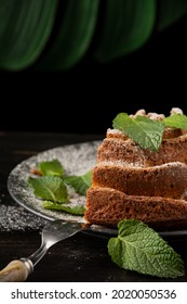 Close-up Of Piece Of Yogurt Sponge Cake On Plate With Sugar, Mint Leaves And Fork, Selective Focus, On Wooden Table And Black Background, Vertical