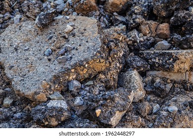 Close-up of pieces of broken asphalt. A pile of old asphalt, gravel and sand on the road. Recycling and reuse crushed concrete rubble, asphalt, building material, blocks. Hardcore waste recycling.