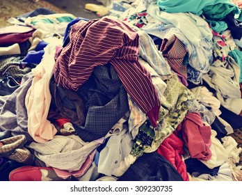 closeup of a pile of different used clothes on sale in a flea market, with a filter effect