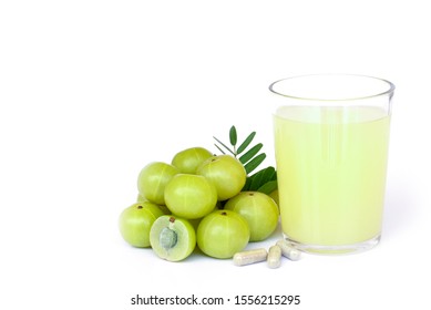 Closeup pile of fresh green Amla or Indian gooseberry fruits (phyllanthus emblica) with capsule and glass of gooseberry juice isolated on white background. Copy space for text.