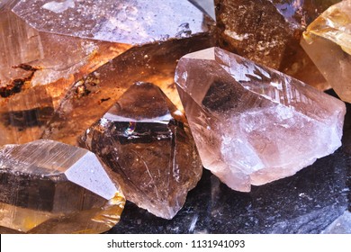 Close-up of a pile of raw translucent Rauchtopaz (Smoky quartz) mineral stone. Macro shooting of specimen of natural mineral. Several smoky quartz raw stones as a background. Selective focus.