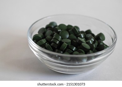 A Close-up Pile Of Round Green Pills In A Transparent Pill Box, Shifted To The Right.